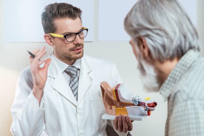 An audiologist shows a male patient a model of an ear at a hearing clinic in the Seattle, WA area.