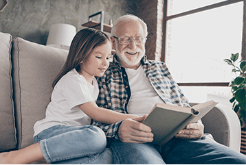 An elderly man with hearing aids helps a child learn to read in the Seattle, WA area.